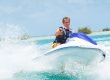Young man in life jacket on a personal watercraft in the water.
