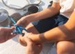 A father shows his son how to tie up dock lines on a boat