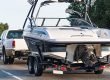 a white truck towing a power boat down the road
